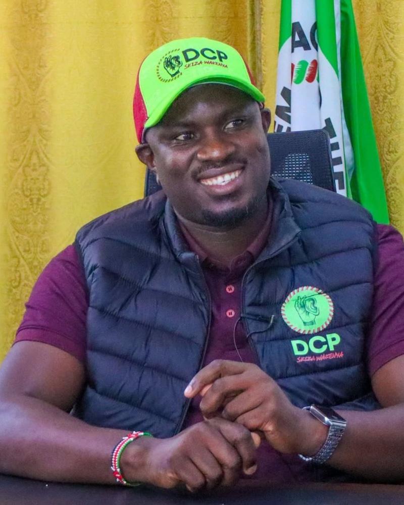 Hezron Obaga in a DCP cap, seated at a desk